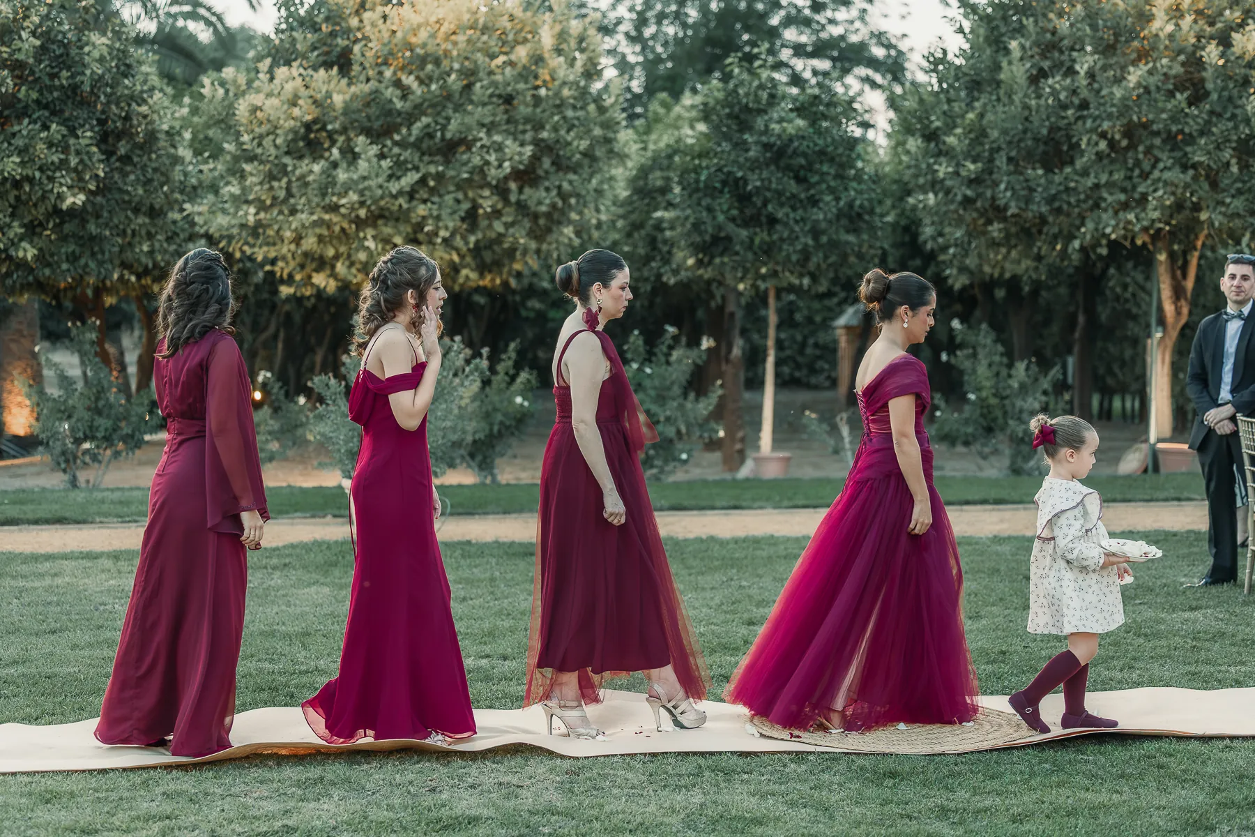 Las damas de honor de burdeos caminan hacia la ceremonia