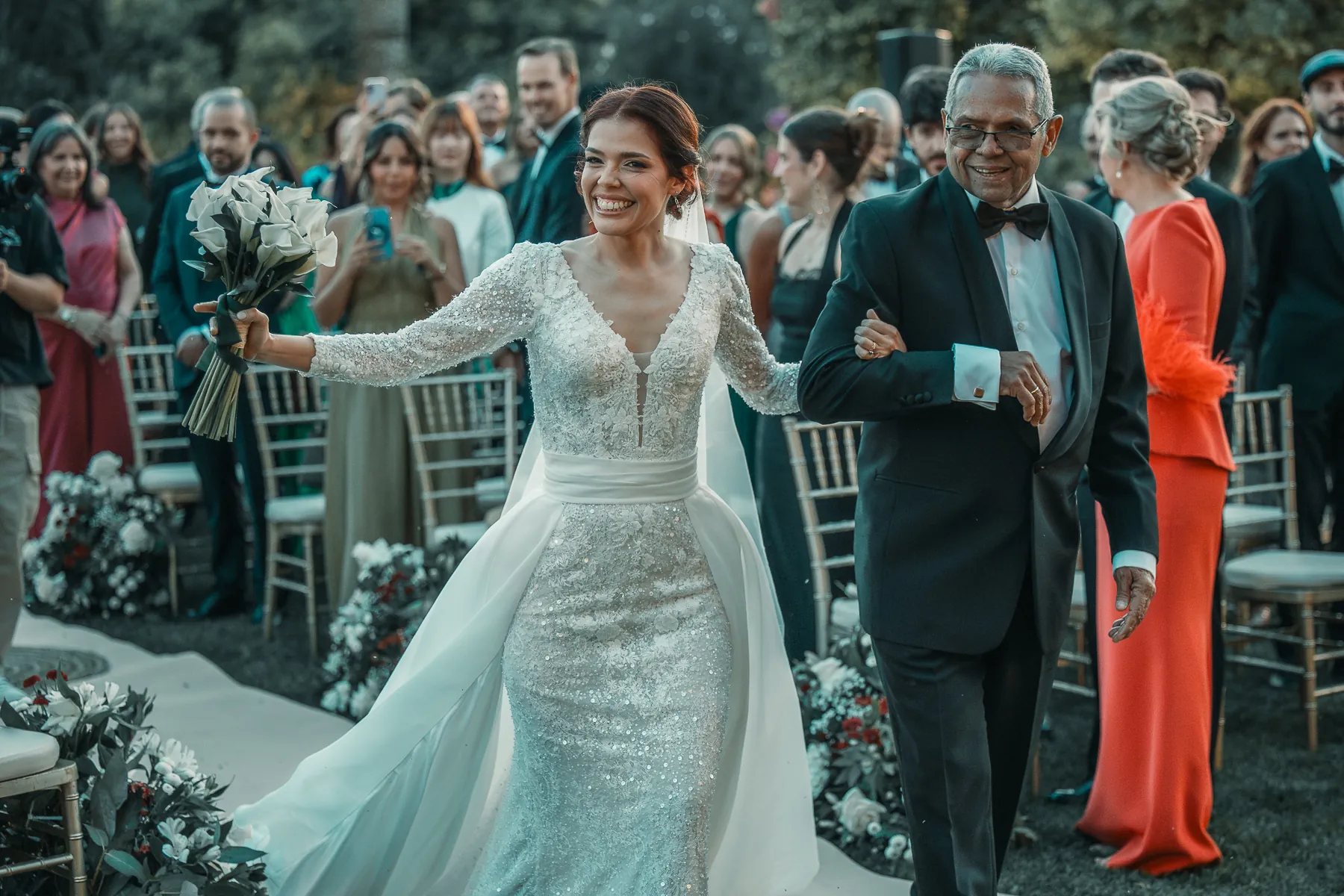 La novia sonríe del brazo de su padre camino del altar
